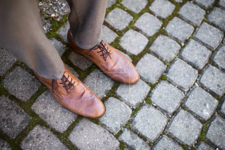 Top view of feet of businessman in brown leather shoes, outdoors.
