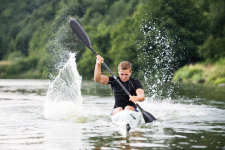 Kanufahrer sitzt im Kanu, paddelt im Wasser. Konzept des Kanufahrens als dynamischer und abenteuerlicher Sport. Rückansicht, Sportler blickt auf Wasseroberfläche, paddelt.