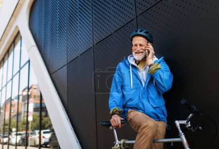 Älterer Mann, Fahrradfahrer, der mit dem Fahrrad durch die Stadt fährt. Senior-Pendler telefoniert.