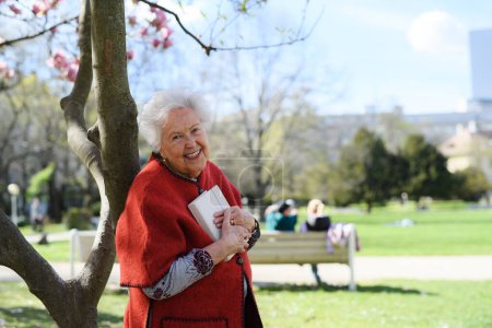 Foto de Mujer mayor leyendo libro al aire libre, en el parque, teniendo momento de relax. Abuela leyendo la Biblia en el cementerio. - Imagen libre de derechos