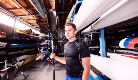 Photo for Portrat of young canoeist standing in the middle of stacked canoes. Concept of canoeing as dynamic, adventurous sport - Royalty Free Image