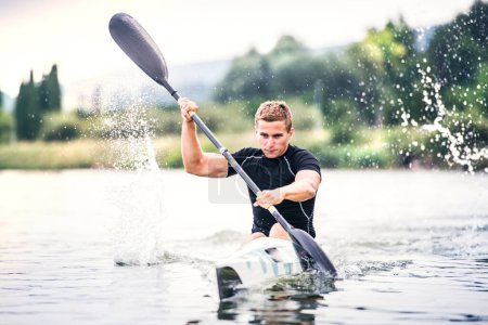 Photo for Canoeist man sitting in canoe paddling, in water. Concept of canoeing as dynamic and adventurous sport. Rear view, sportman looking at water surface, paddling. - Royalty Free Image