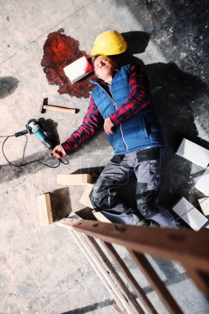 Ein bewusstloser Arbeiter liegt nach einem Unfall auf der Baustelle am Boden, Blut am Kopf. Arbeitsunfälle, Arbeitsunfälle.