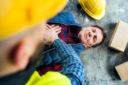 Kollege führt CPR an einem verletzten Arbeiter durch, der nach einem Unfall am Boden liegt. Konzept für Arbeitssicherheit und Gesundheitsschutz am Arbeitsplatz.