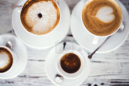 Tazas con café espresso caliente, capuchino y café con leche en la mesa.