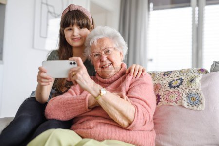 Foto de Abuela con linda chica tomando selfie con teléfono inteligente. Retrato de una anciana que pasa tiempo con una nieta. - Imagen libre de derechos