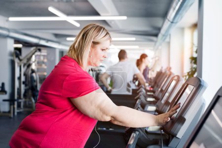 Photo for Overweight woman exercising on treadmill machine in gym. - Royalty Free Image