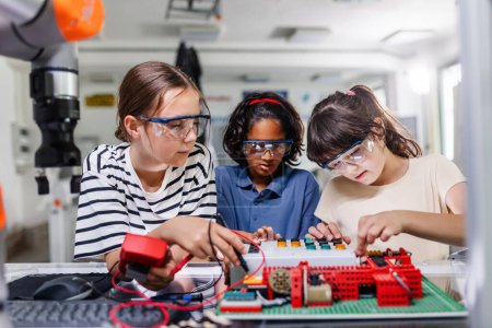 Compañeros de clase trabajando togeter en placa de circuito, construyendo robot en un club de robótica después de la escuela. Niños aprendiendo robótica en la escuela primaria.