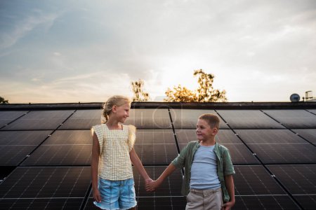 Deux jeunes frères et s?urs sur le toit avec des panneaux solaires, se regardant les uns les autres.Un avenir durable pour le concept de prochaine génération.