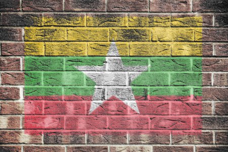 A Myanmar flag on old brick wall background yellow green red stripe white star