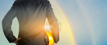 Téléchargez les photos : Concept d'ingénieur tenant un casque de sécurité Rainbow sky backgroun - en image libre de droit