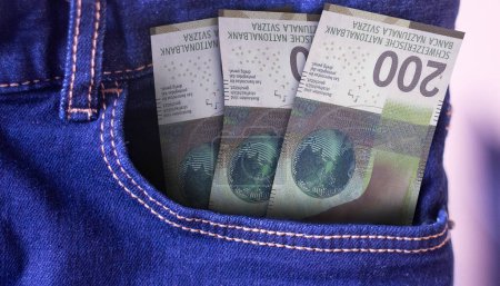 Téléchargez les photos : Billet de 200 francs suisses dans un jean poche un concept de dépense - en image libre de droit