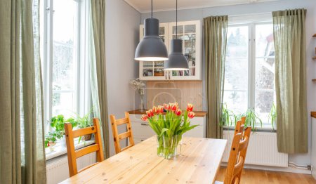 Téléchargez les photos : Bannière tulipes rouges dans un vase sur table de cuisine en bois deux fenêtres - en image libre de droit