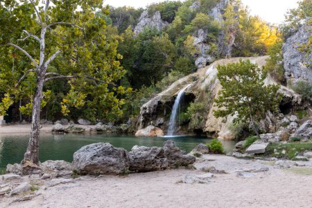 Water cascading over rocks into a natural pool at Turner Falls in Oklahoma, beautiful nature, water and rocks among trees.