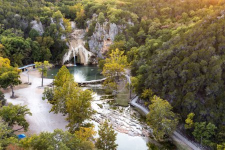 Luftaufnahme von Wald auf Hügeln und natürlichem Pool bei Turner Falls in Oklahoma, schöne Natur, Straße in Wassernähe zwischen Bäumen im Turner Waterfall Park.