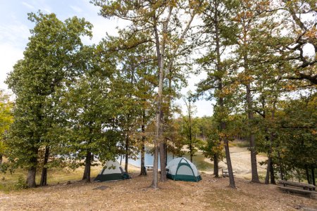 Foto de Tiendas de campaña cerca de un hermoso lago entre árboles, camping, concepto de vacaciones de aventura, lago de arco roto en Oklahoma, EE.UU.. - Imagen libre de derechos