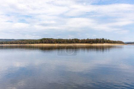 Téléchargez les photos : Beau paysage avec ciel bleu et surface lisse du lac, forêt et littoral au loin, lac Broken bow, Oklahoma, États-Unis. - en image libre de droit
