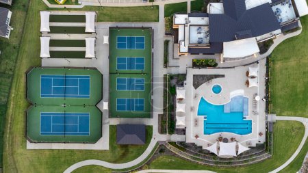 Téléchargez les photos : Vue aérienne de grands courts de tennis, piscine au centre récréatif communautaire avec des demeures avec des zones de salon en plein air en été. - en image libre de droit