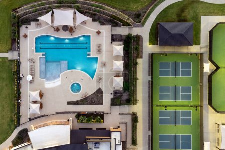 Photo for Aerial view of large tennis courts, swimming pool at community recreational center with mansions with lounge areas in the summertime outdoor. - Royalty Free Image