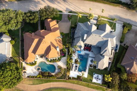 Photo for Aerial drone view of luxury mansions with swimming pools surrounded by green grass and trees in the summertime. - Royalty Free Image