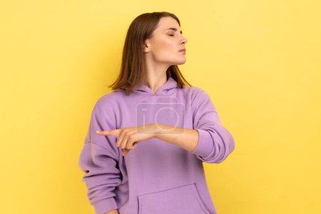 Photo for Get out. Portrait of upset vexed woman showing exit, demanding to leave her alone, has resentful irritated expression, wearing purple hoodie. Indoor studio shot isolated on yellow background. - Royalty Free Image
