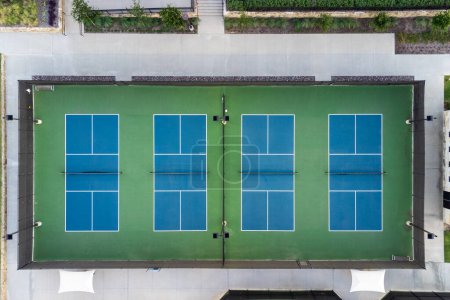 Téléchargez les photos : View from above, aerial view of four blue public, empty tennis courts, tennis playgrounds in the summertime outdoor. - en image libre de droit