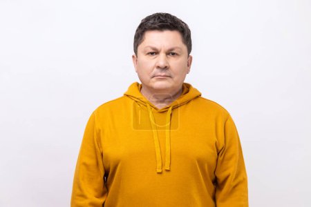 Téléchargez les photos : Portrait of serious self assured unsmiling man with dark hair seriously looking at camera, confidence, wearing urban style hoodie. Indoor studio shot isolated on white background. - en image libre de droit