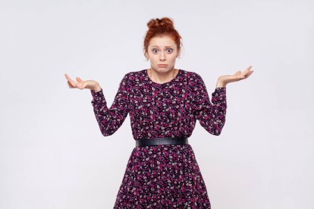 Photo for Maybe, don't know. Unsure uncertain redhead woman wearing dress raising hands with confused perplexed puzzled expression, not sure about decision. Indoor studio shot isolated on gray background. - Royalty Free Image