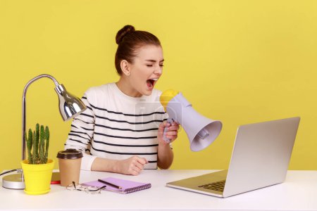 Téléchargez les photos : Portrait of young excited woman screaming loudly in megaphone, announcing important advertisement, having video call with partners. Indoor studio studio shot isolated on yellow background. - en image libre de droit
