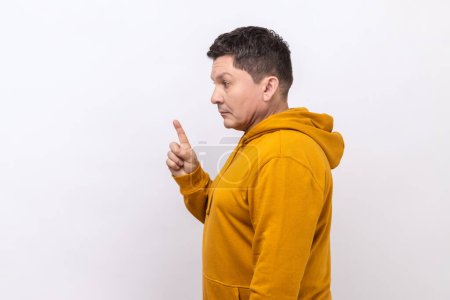 Photo for Side view of angry middle aged man scolding for mistake, dissatisfied with behavior, blaming showing admonishing gesture, wearing urban style hoodie. Indoor studio shot isolated on white background. - Royalty Free Image