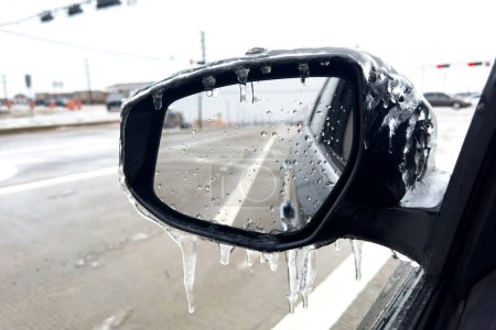 Car on the street, covered automobile mirror by icy rain, reflection of road, ice-crusted ground in Texas.