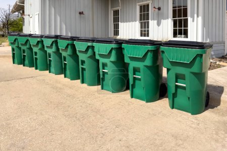 Rangée de poubelles vertes et propres près de la maison, élimination des ordures dans des conteneurs verts dans un complexe résidentiel.