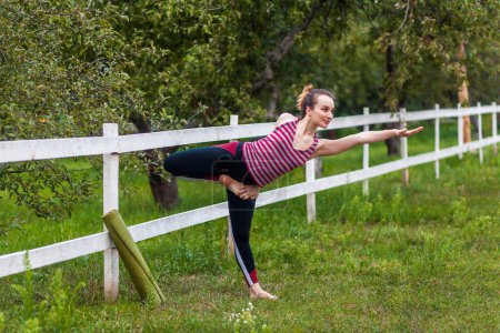 Photo for Full length portrait of young sporty attractive woman wearing sportswear practicing yoga, doing Natarajasana exercise, Lord of the Dance pose, working out in park with beautiful nature. - Royalty Free Image