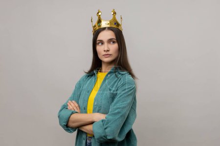 Photo for Woman with crown on head, standing with crossed arms, self confidence in success, self-motivation and dreams to be best, wearing casual style jacket. Indoor studio shot isolated on gray background. - Royalty Free Image