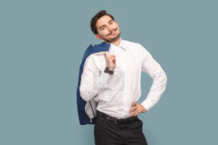 Photo for Portrait of satisfied smiling confident man with mustache standing holding his jacket over shoulder, looking at camera, wearing Indoor studio shot isolated on light blue background. - Royalty Free Image
