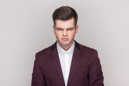 Photo for Portrait of sad upset depressed handsome man standing looking at camera with sorrow and sadness, being offended, wearing violet suit and white shirt. Indoor studio shot isolated on grey background. - Royalty Free Image
