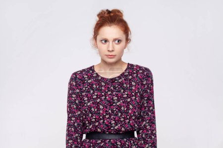 Photo for Portrait of worried serious young adult attractive ginger woman wearing dress looking away with scared, frighten expression, thinking. Indoor studio shot isolated on gray background. - Royalty Free Image