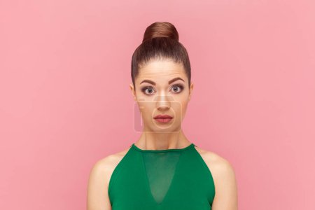 Photo for Portrait of attractive shocked amazed woman standing and looking at camera with big eyes, sees something astonishing, wearing green dress. Indoor studio shot isolated on pink background. - Royalty Free Image