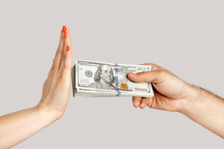 Photo for Closeup of woman hand refusing money, man hand offering dollar banknotes, corruption. showing Indoor studio shot isolated on gray background. - Royalty Free Image