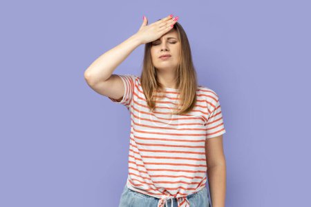 Photo for Portrait of sad upset worried blond woman wearing striped T-shirt standing with facepalm gesture, forgot about something important. Indoor studio shot isolated on purple background. - Royalty Free Image