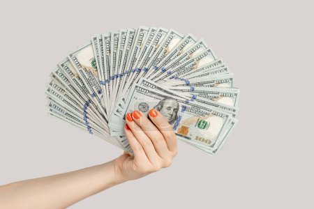 Photo for Closeup of woman hand showing big fan of dollar banknotes, salary, earning, money. Indoor studio shot isolated on gray background. - Royalty Free Image