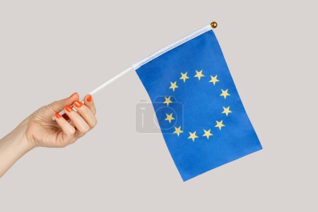 Téléchargez les photos : Gros plan de la main de la femme montrant le drapeau de l'UE, voyageant vers les pays d'Europe, immigration. Studio intérieur tourné isolé sur fond gris. - en image libre de droit