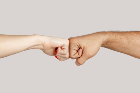 Photo for Closeup of unrecognizable woman and man handshaking with fists. Indoor studio shot isolated on gray background. - Royalty Free Image