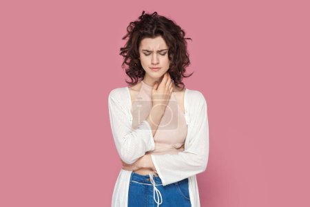 Photo for Portrait of sad upset unhappy woman with curly hair wearing casual style outfit standing looking down, crying, hearing bad news. Indoor studio shot isolated on pink background. - Royalty Free Image