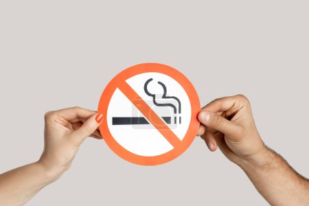 Photo for Closeup of woman hands showing card with no smoking sign, healthy lifestyle, healthy habits. Indoor studio shot isolated on gray background. - Royalty Free Image