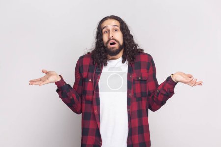 Photo for I do not know. Unaware perplexed bearded man spreads palms sideways, has no idea what to do, thinks how to act in troublesome situation. Indoor studio shot isolated on gray background. - Royalty Free Image