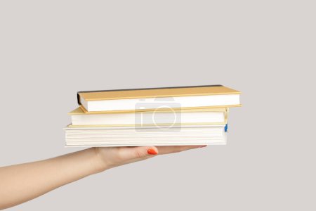 Photo for Closeup of woman hand showing lots textbooks or organizers, education, reading literature. Indoor studio shot isolated on gray background. - Royalty Free Image