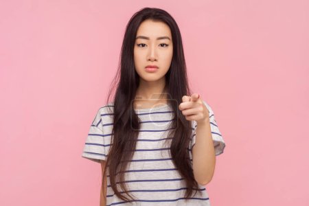 Photo for Portrait of bossy strict woman with long brunette hair pointing at camera choosing you displeased expression, wearing striped T-shirt. Indoor studio shot isolated on pink background. - Royalty Free Image