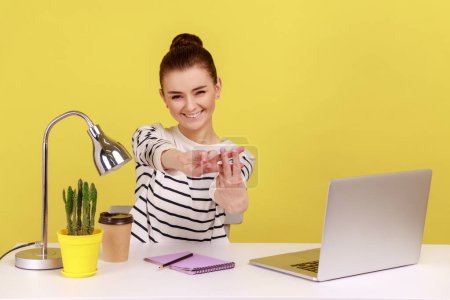 Photo for Smiling happy woman office worker showing hashtag sign with fingers sitting at workplace, keeping own blog, tagging post for easy search. Indoor studio studio shot isolated on yellow background. - Royalty Free Image