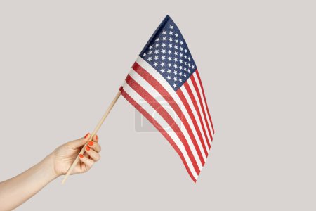 Téléchargez les photos : Gros plan de la main de la femme montrant drapeau américain, voyageant aux États-Unis, immigration. Studio intérieur tourné isolé sur fond gris. - en image libre de droit